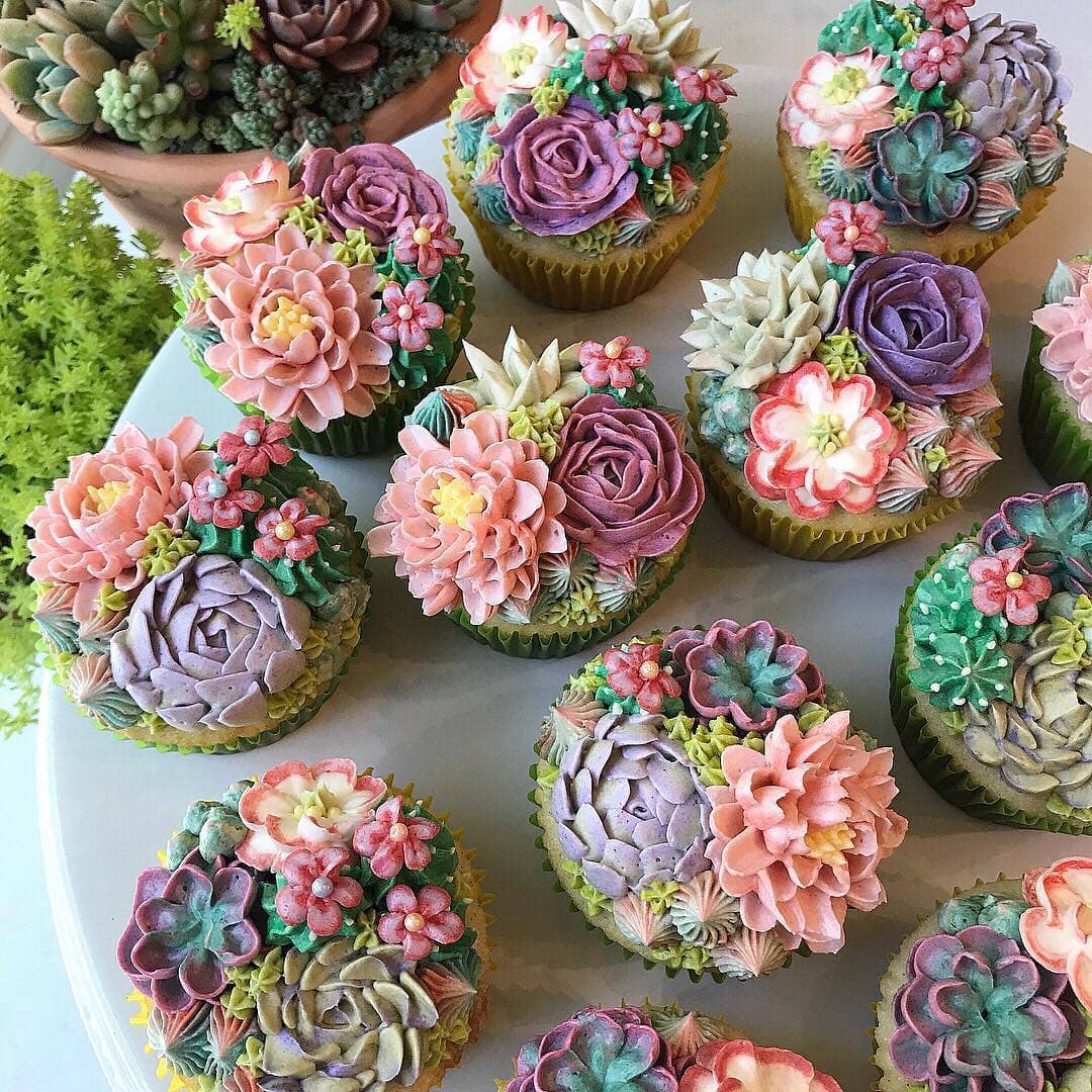 A table adorned with cupcakes, each topped with vibrant succulents and delicate flowers, symbolizing healing and nature's beauty. 